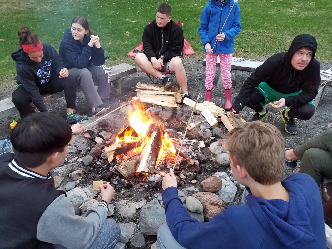 teens around a campfire making smores